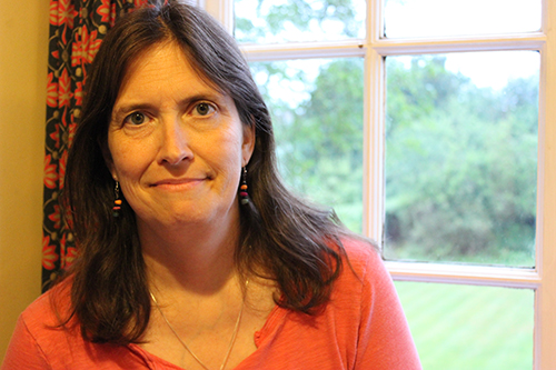 Portrait of Susan Perabo in front of a window with trees in the distance