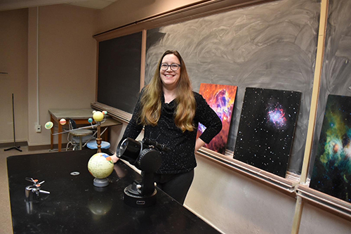 Angelle Tanner is pictured in a classroom lab with photos of space in the background