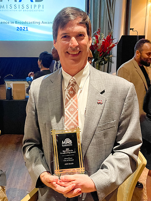 Terry Likes, MSU professor and communication department head, smiles while holding an award from the Mississippi Association of Broadcasters. 