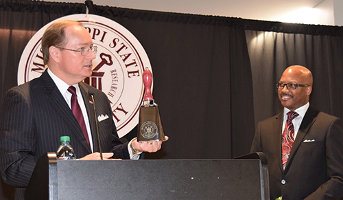 Mississippi State University President Mark E. Keenum presented Mississippi Deputy Commissioner of Higher Education Marcus L. Thompson with a special cowbell after Thompson delivered the keynote address at the 25th Annual Dr. Martin Luther King Jr. Unity Breakfast held at The Mill at MSU Conference Center on Monday, Jan. 21. Over 1,500 people attended the program, which focuses on unity and service. (Photo by Sid Salter)