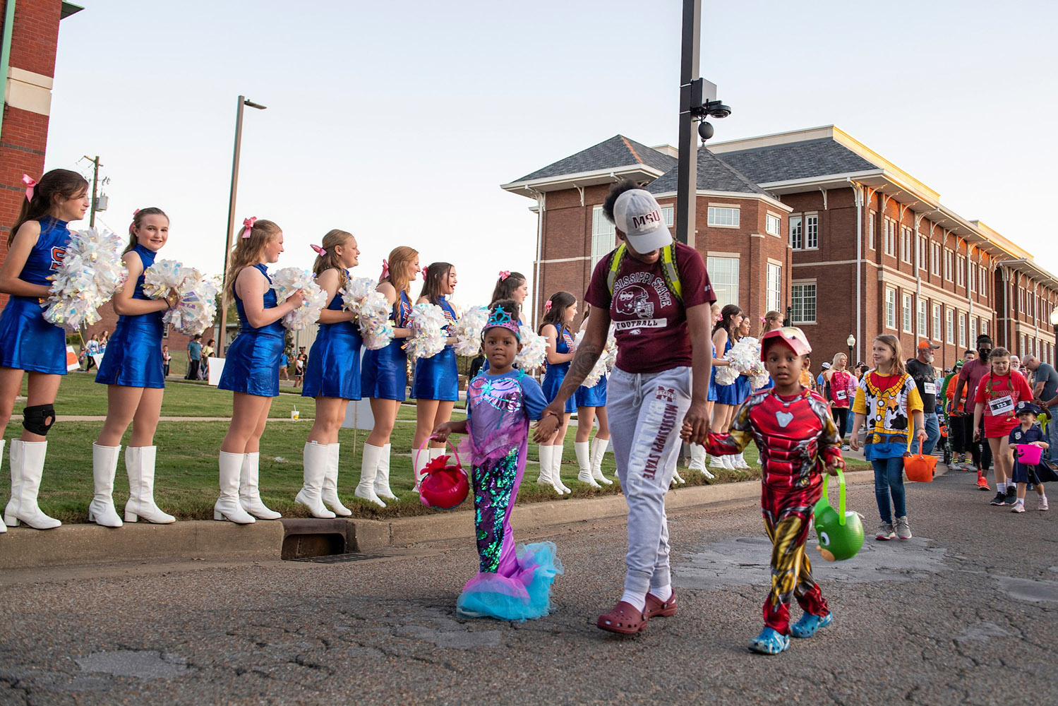 Children dressed in costumes walk down the road with a mother during Trik or Trot