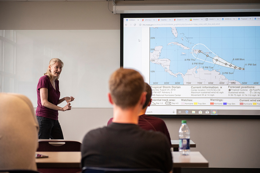 Kim Wood discusses a tropical storm in front of a class.