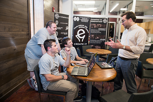 Conor Ferguson, standing left, along with Joseph Cuty and Logan Smith, seated from left, talk with MSU Center for Entrepreneurship and Outreach Director Eric Hill in McCool Hall. Along with a team of entrepreneurship advisory board members and other mentors from the Bulldog family, Hill has helped the WISPr Systems business team successfully navigate the start-up process. (Photo by Megan Bean)