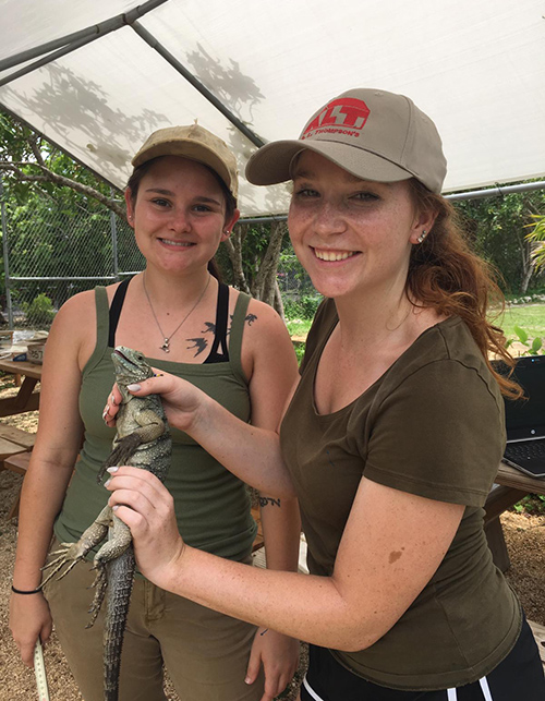 Blaklie E. Mitchell, left, and Katelyn S. Provine hold a Blue Iguana while standing under a tent.