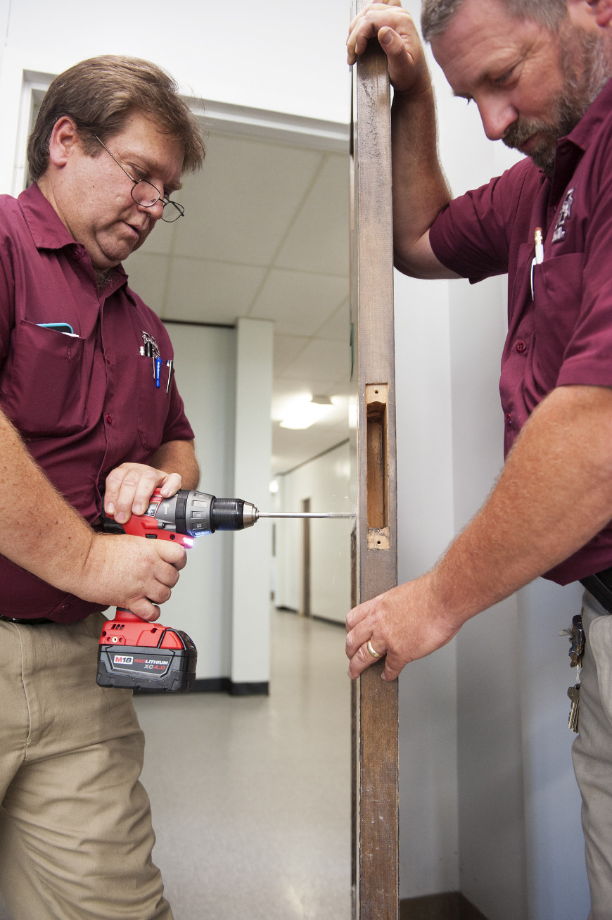 After a review of Mississippi State University’s response to a potential active shooter threat last week, MSU President Mark E. Keenum met with other university officials and area law enforcement agencies to formulate a long-term plan to enhance safety and security at MSU – a plan the president called “TLC” – training, locks and communications. MSU Physical Plant staffers Robert Moore, left, and Randal Nickels, right, are shown installing new locks in Carpenter Hall as part of that plan. [Photo by Beth Wynn]