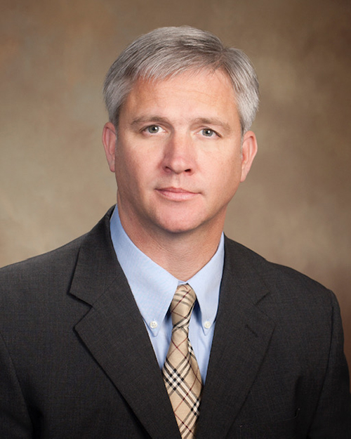 Studio portrait of Mike Tagert with a tan backdrop