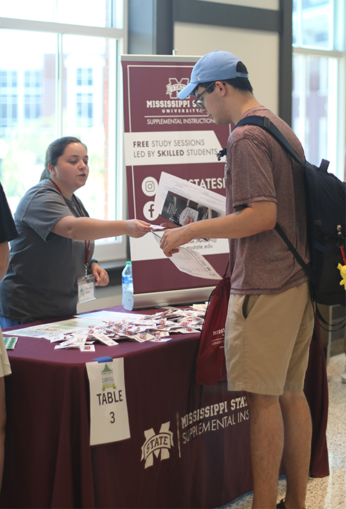 A student gets information from an MSU staff member at a table
