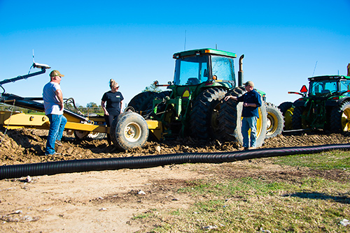 Darrin Dodds, Darla Huff, and Jason Krutz stand by heavy equipment amidst the installation project at Mississippi State’s R.R. Foil Plant Science Research Center. 