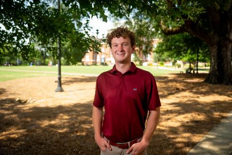 Young man standing in front of a college building