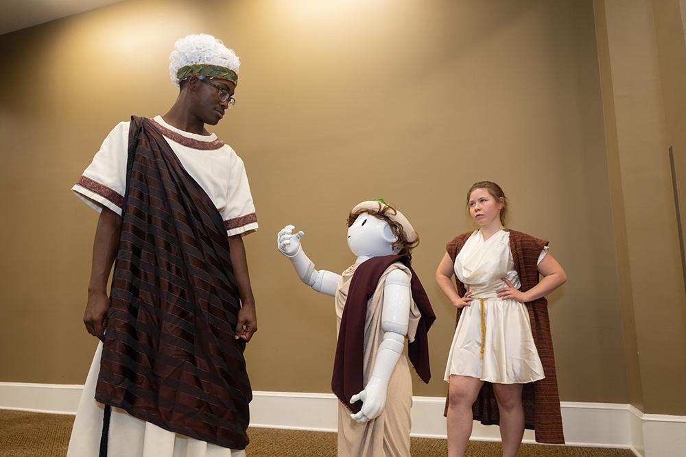 Two actors recreate a scene from an upcoming play along side a robot.