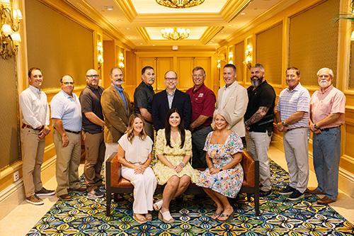 Members of the Mississippi Lumber Manufacturers Association board pose for a group photo inside a large hallway.