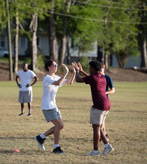 A football player and coach high five after a successful play.