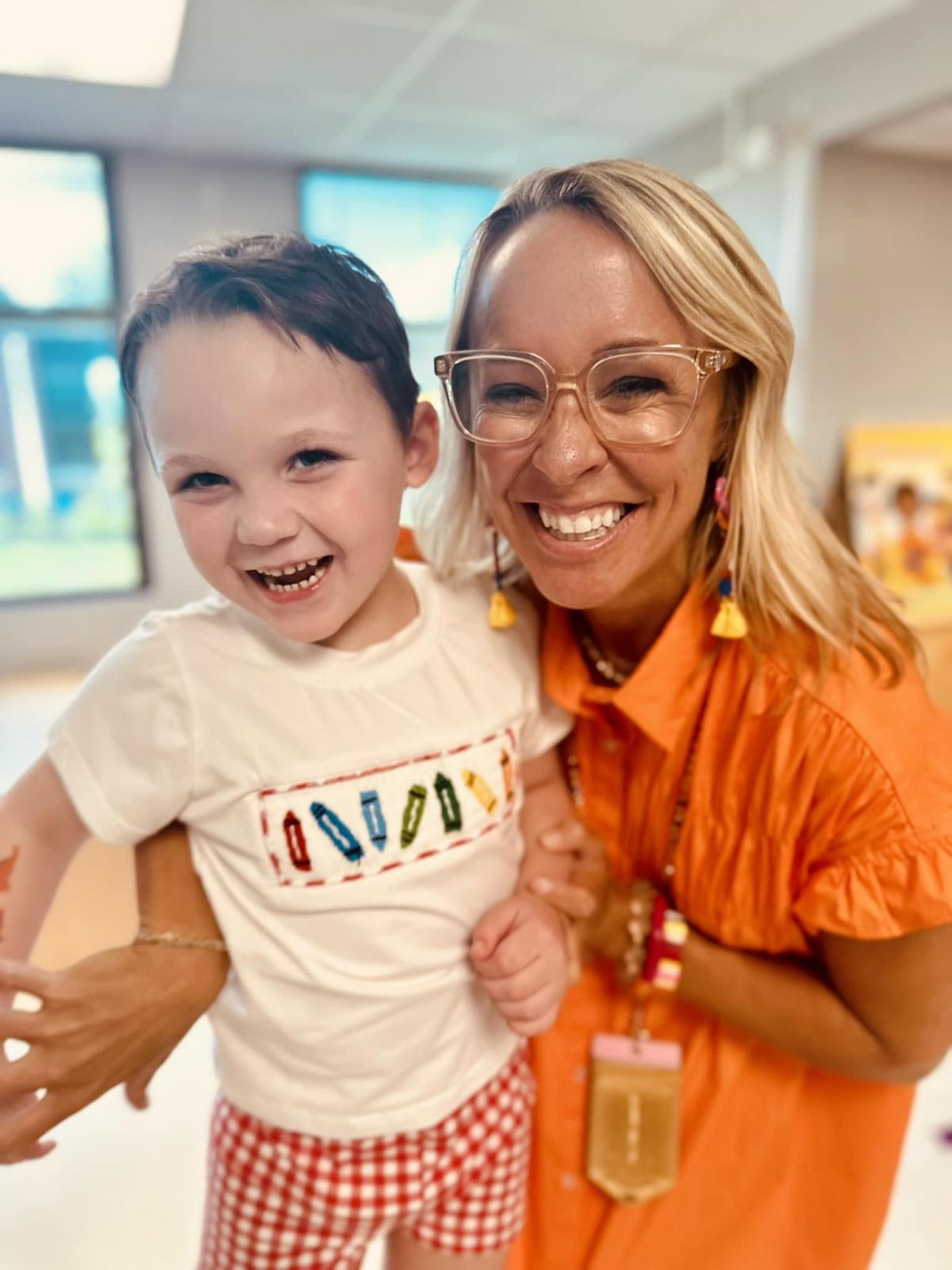 Little boy stands with his teacher
