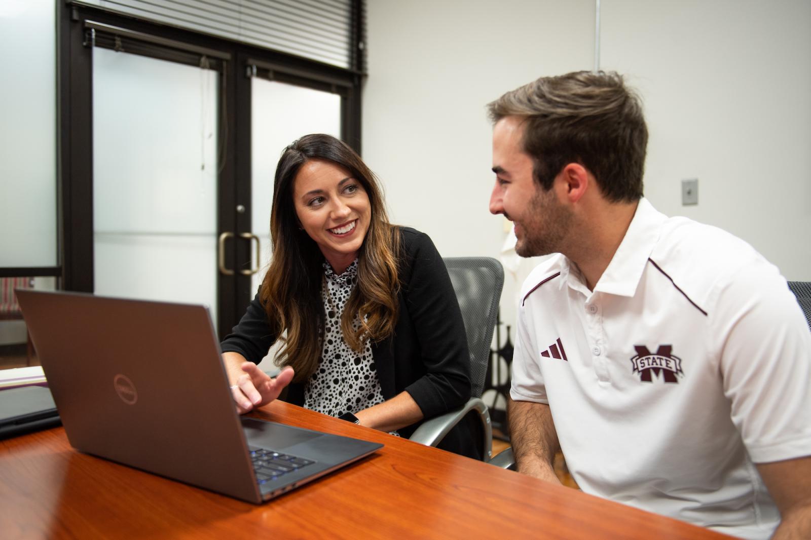 girl laughing with man looking at laptop