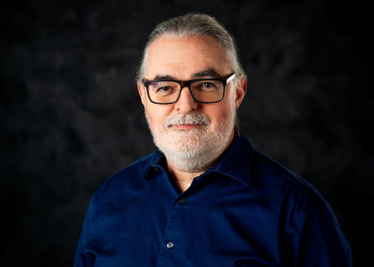 Man in blue shirt in front of grey background