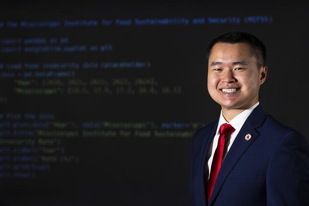 Devin Chen stands in front of a projection of computer software code.