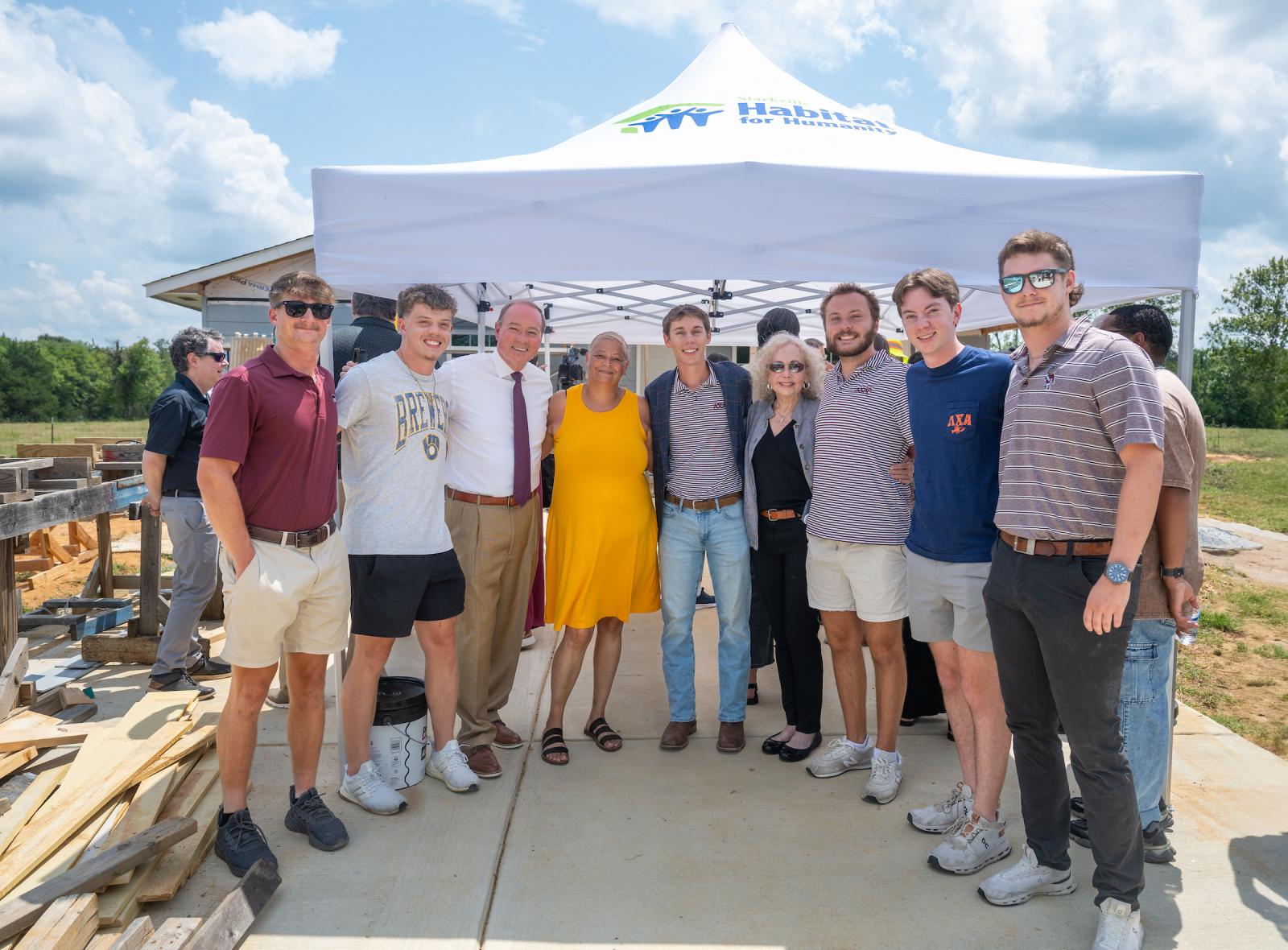 young men and woman standing in front of a tent