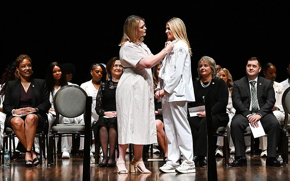 Kayla Carr, Mississippi State University-Meridian professor of nursing, pins graduate Olivia Adams of Philadelphia at Thursday&#039;s [Aug. 7] inaugural Master of Science in Nursing pinning and graduation ceremony.