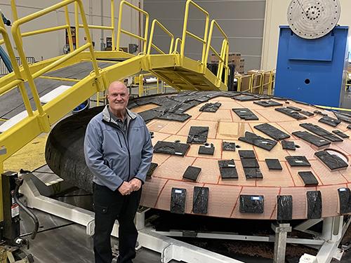 Two-time Mississippi State graduate Terry Abel stands in front of NASA’s Orion Artemis I heat shield, which will protect astronauts during re-entry as part of future deep space missions.