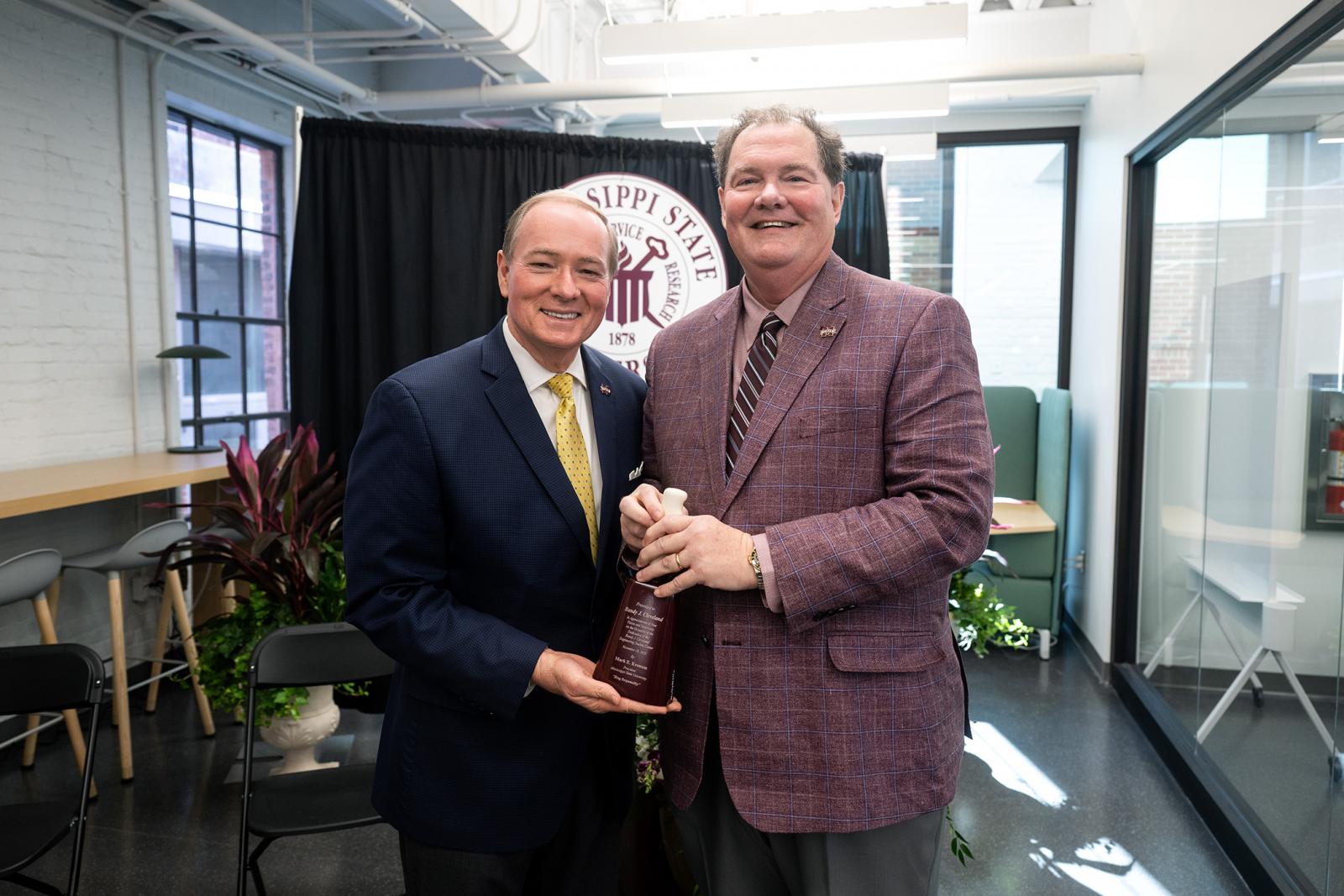 MSU President Mark E. Keenum, left, presents a cowbell to Randy Cleveland on the occasion of today’s [Nov. 18] ribbon-cutting ceremony for the university’s Randy J. Cleveland Engineering Student Center.