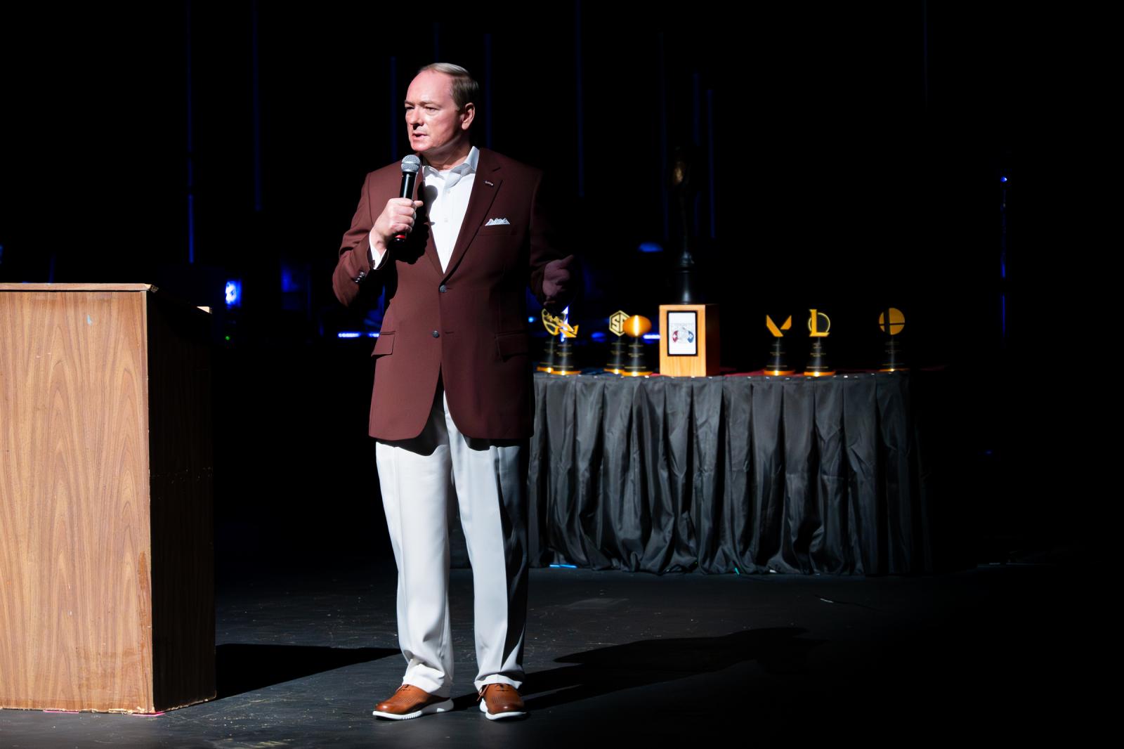 man in maroon jacket on stage