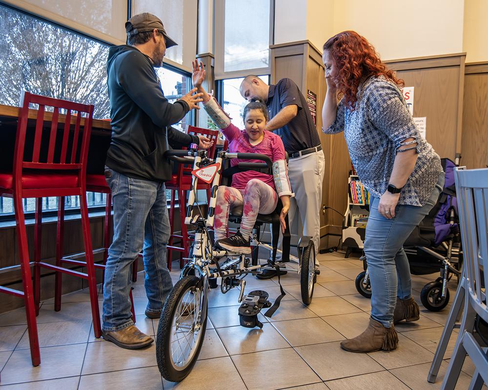 Alyssa Greer, center, receives a special adapted bicycle.