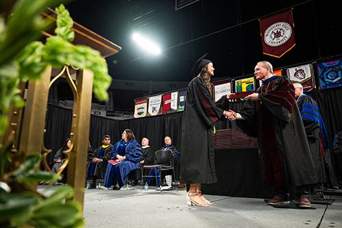 MSU President Mark E. Keenum hands a diploma to a 2025 fall graduate Dec. 12 during commencement ceremonies at Humphrey Coliseum.