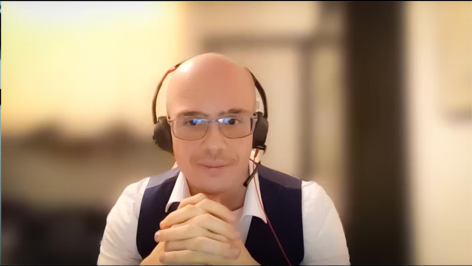 man with headphones looking at camera and crossing hands