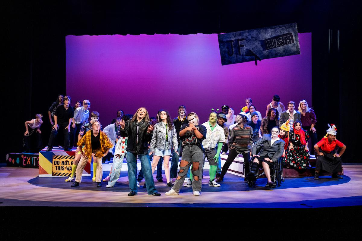 group of students on a theatre stage singing and dancing