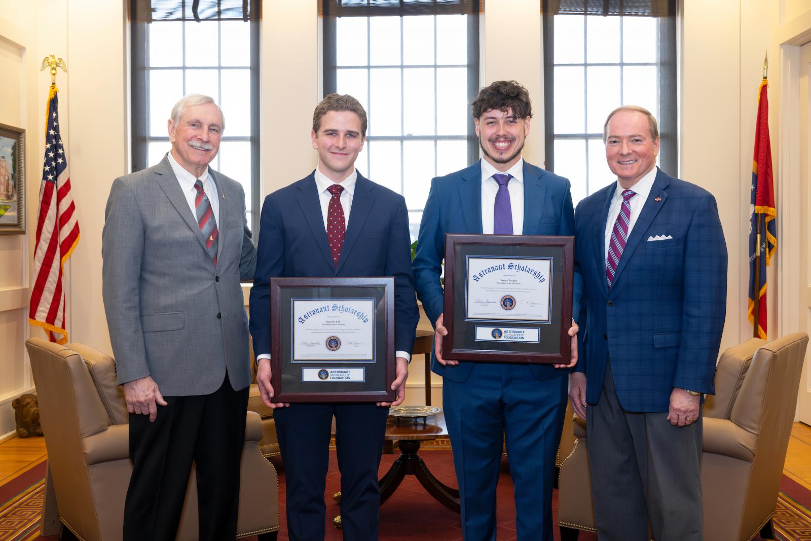 two young men center with plaques celebrate with astronaut and university president