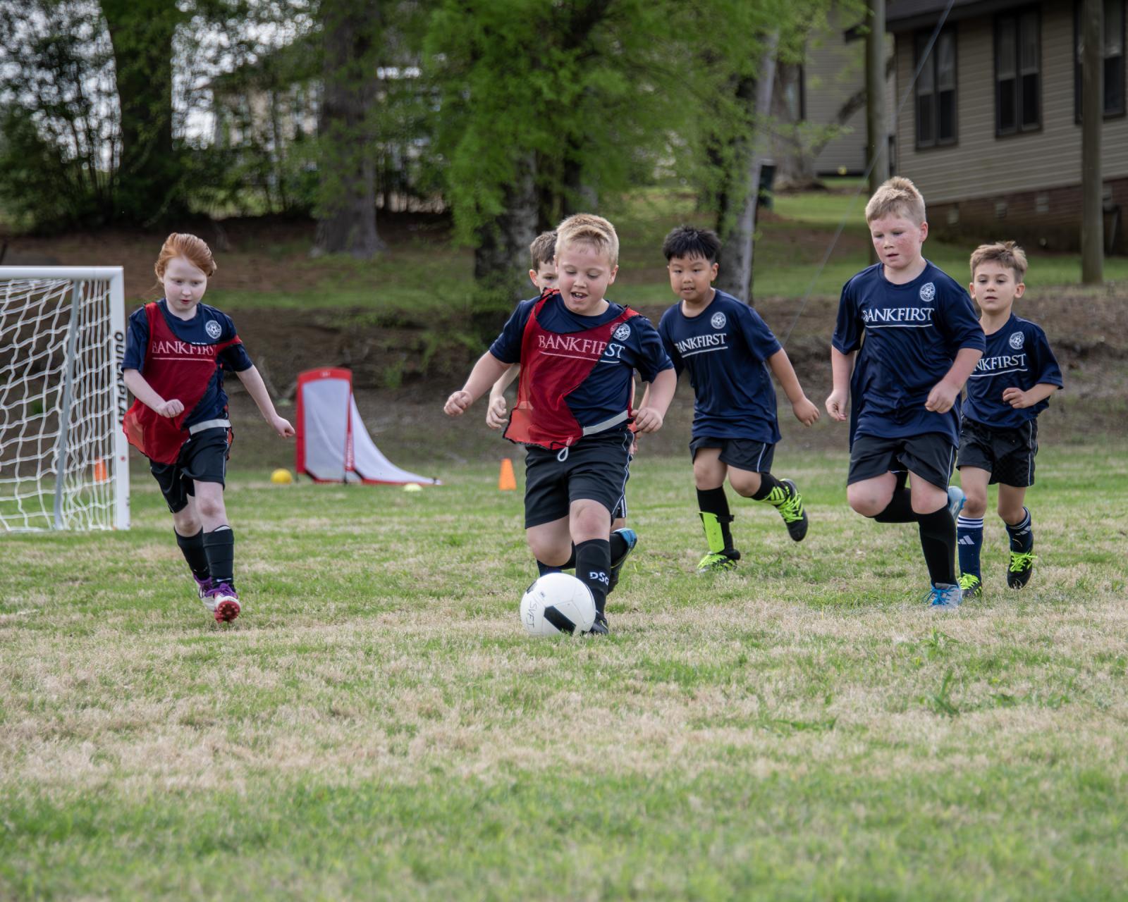 photo of children playing soccer on a pitch