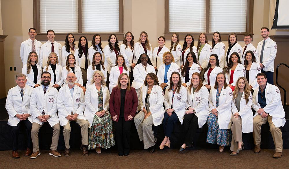 Mississippi State University-Meridian Master of Physician Assistant Studies students gather with faculty for a formal photograph following a spring White Coat Ceremony signaling the students are ready to leave the didactic phase of their education and enter clinical rotations.