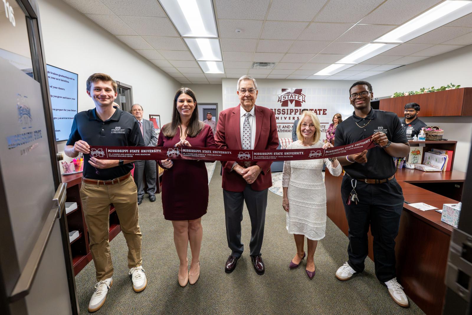A photo of five people holding a ribbon for the healthcare pathways resource ribbon cutting