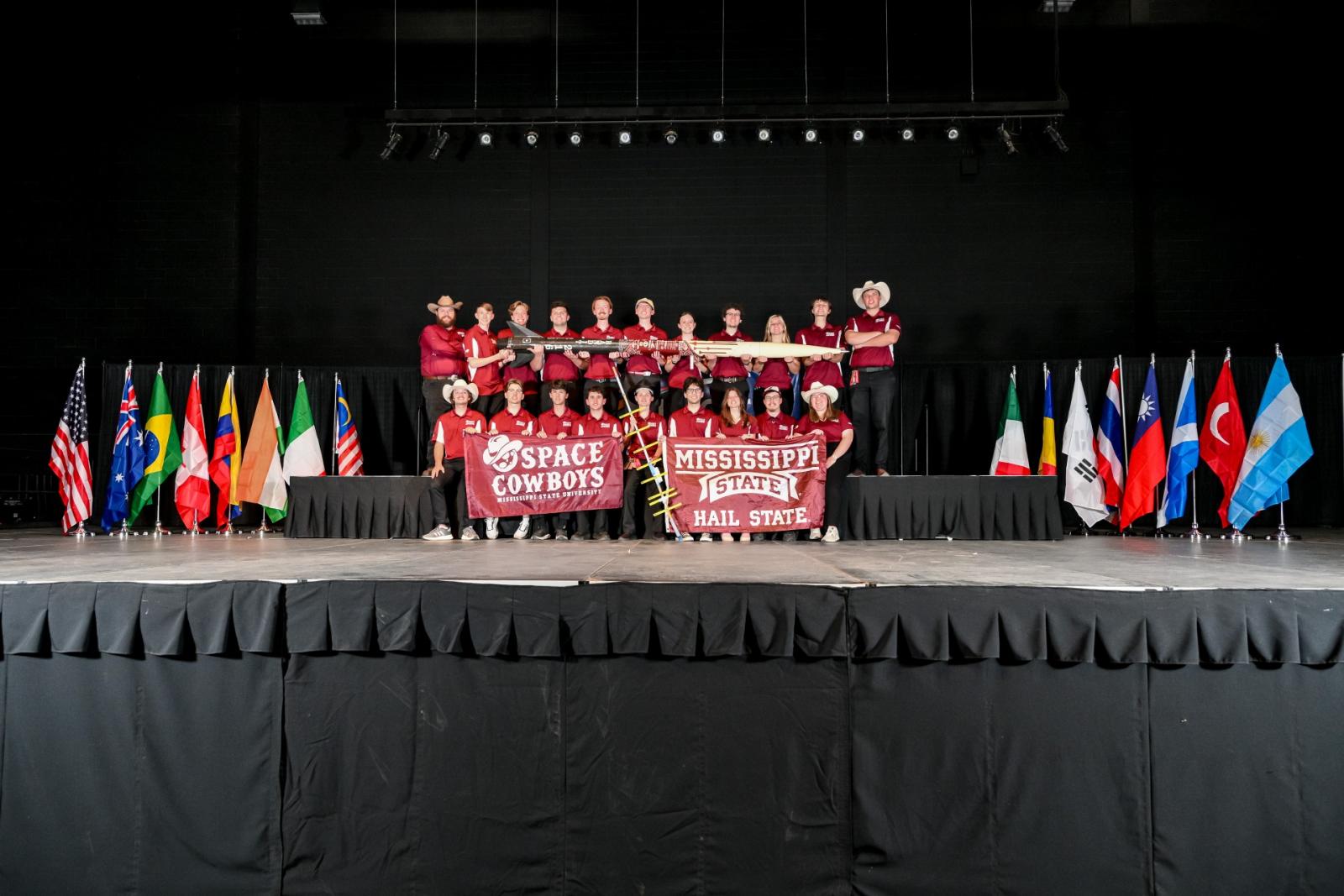 photo of MSU space cowboys team holding a rocket and banners on a stage