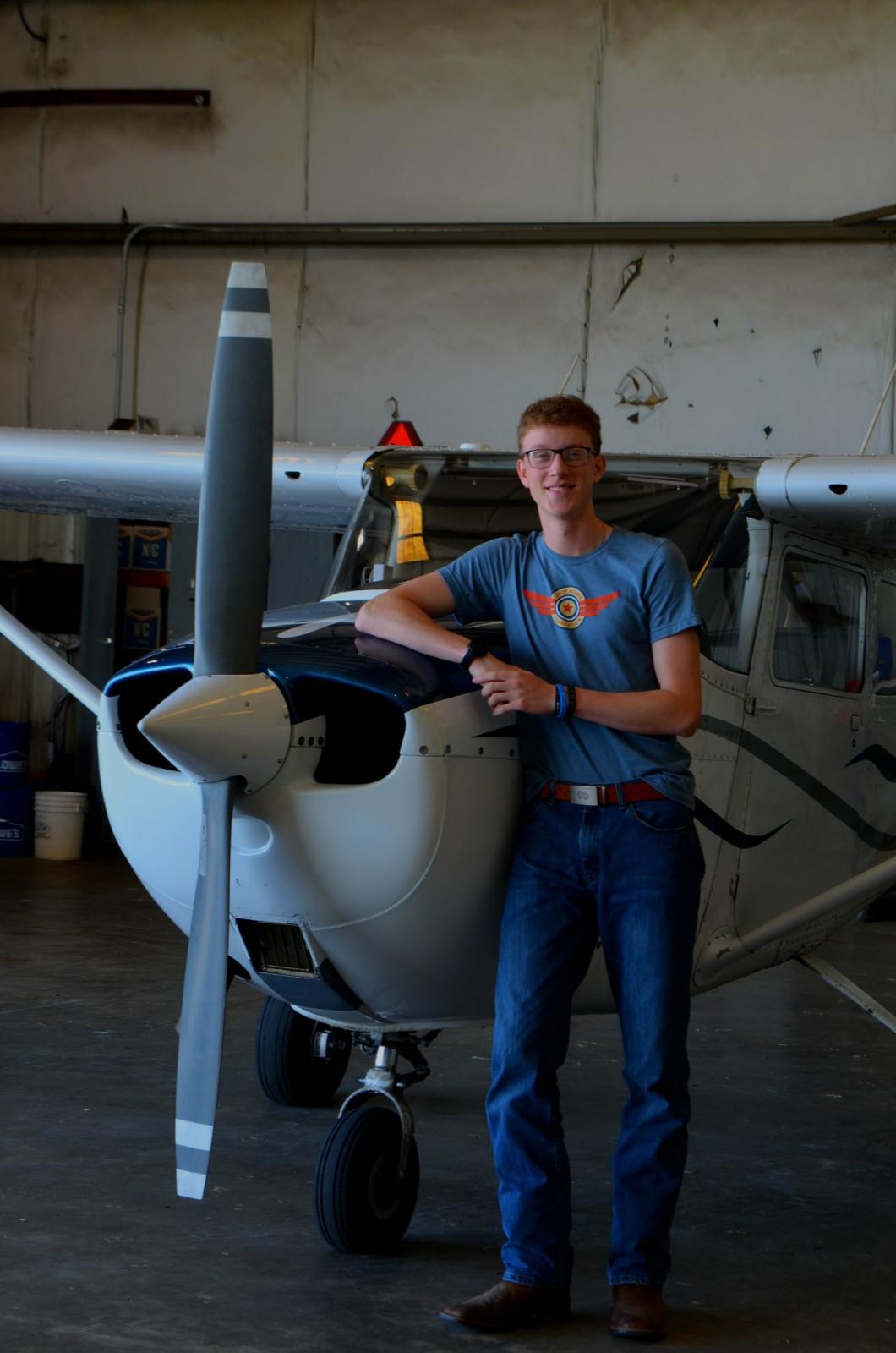Bradyn Long stands in front of an airplane