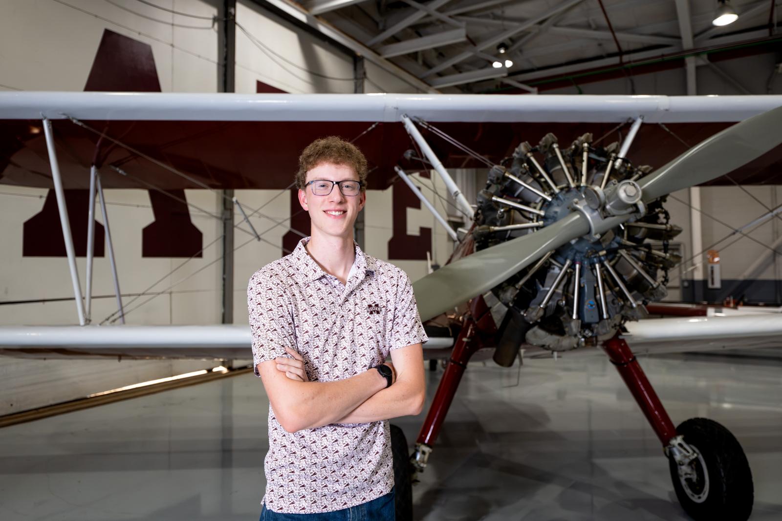 Bradyn Long standing in front of an airplane.