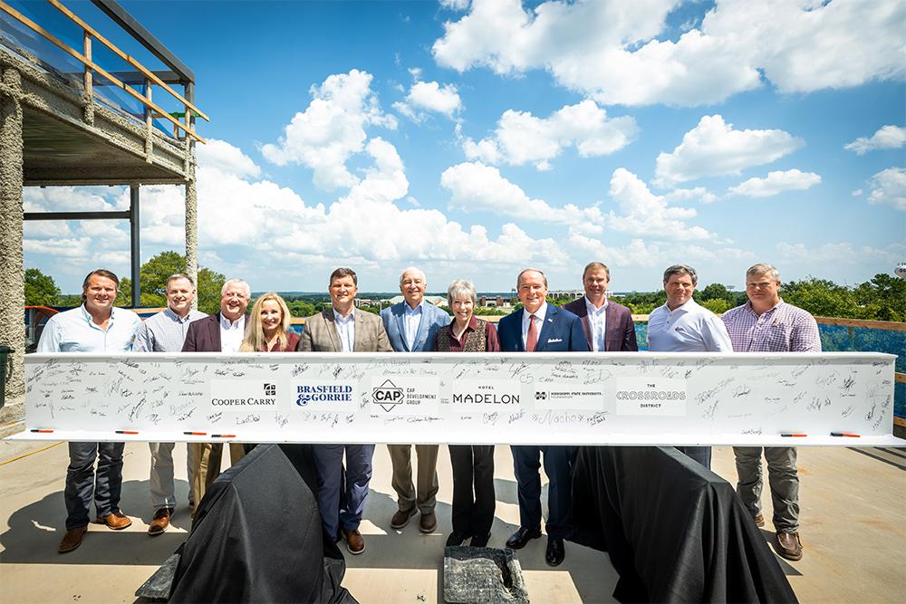 Leaders pose with a signed steel beam at Hotel Madelon