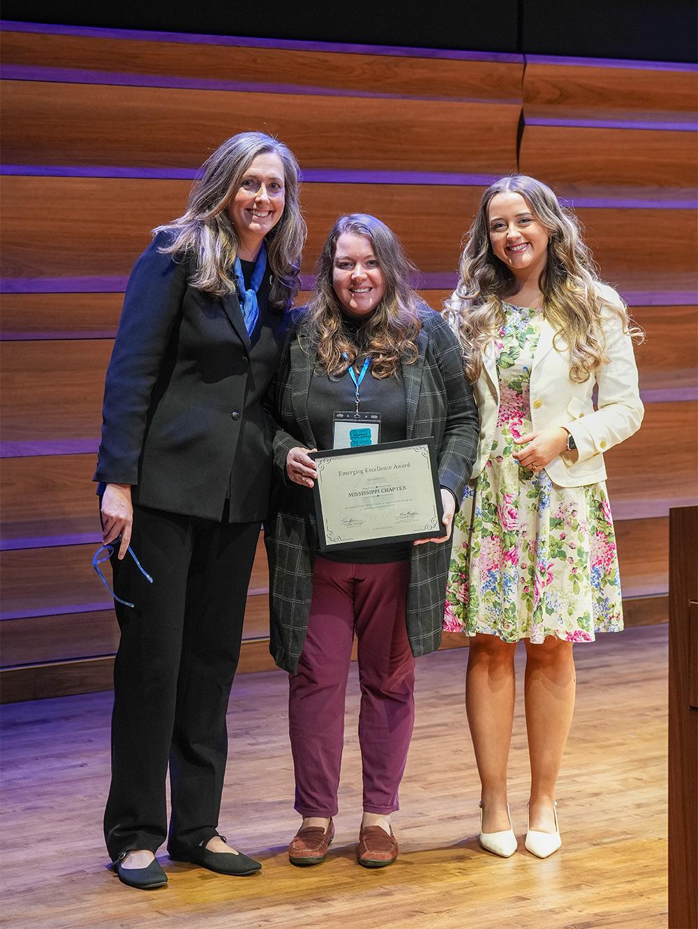 MSU International Institute Deputy Director Masey Smith, center, accepts the Emerging Excellence Award Friday [Oct. 23] at the national Fulbright Association’s annual conference in Washington, D.C. from Fulbright Association Executive Director Tammy Hettinger, left, and Fulbright Association Assistant Director for Membership and Administration Fiona Breslin.