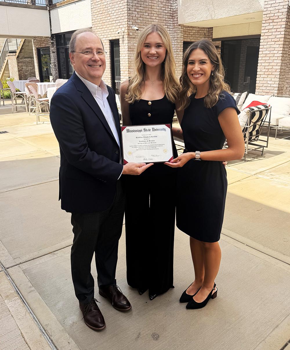 MSU College of Arts and Sciences Dean Rick Travis, left, and Advisor Kate Sawaya, right, present Brandon native Caroline Griffith her bachelor’s degree in interdisciplinary studies.
